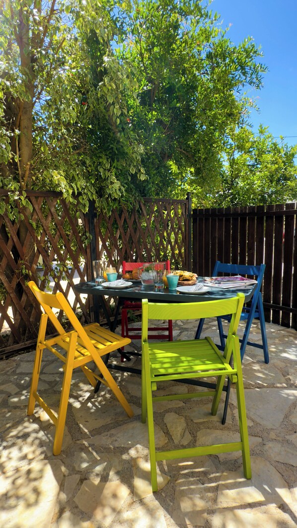 An outdoor patio with a table set for two, surrounded by a wooden fence and trees.