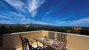 A terrace with a table and chairs, overlooking a scenic landscape with mountains and a body of water.
