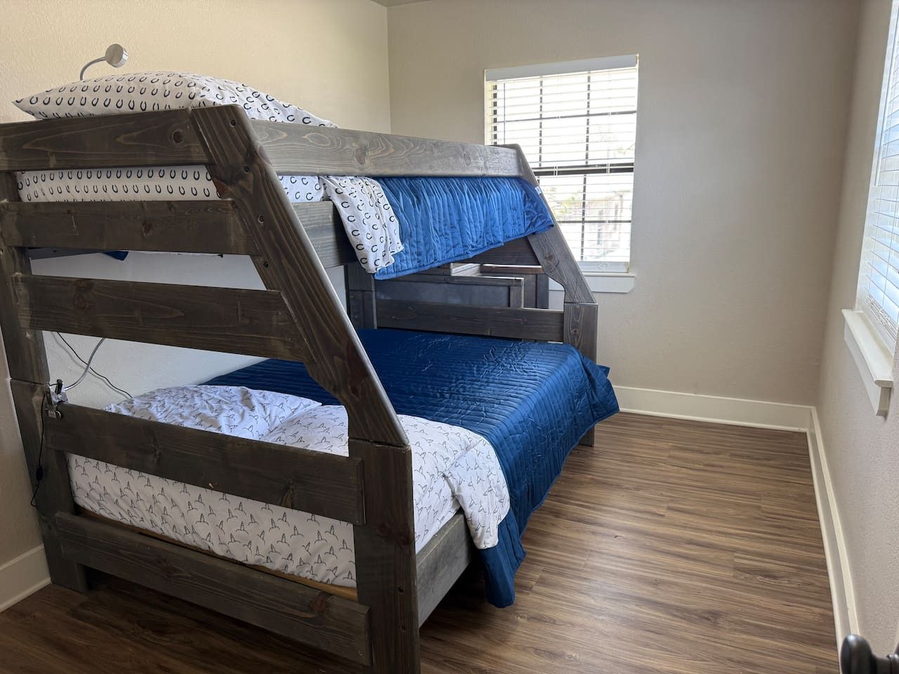 A bunk bed with a wooden frame and blue bedding.
