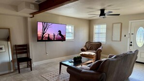 A living room with a TV, leather sofas, a coffee table, and a wooden chair. - Minutes off I-35W - close to all the area attractions! (Argyle)