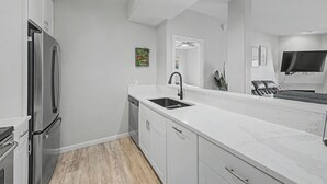 A modern kitchen with a built-in dishwasher, a stainless steel refrigerator, a white countertop, and a black faucet. - Modern 2BR/2BA Retreat: Ground Floor / Pool, Spa, Gym / North Scottsdale Getaway (Scottsdale)