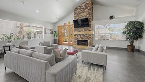 A spacious living room with a stone fireplace, comfortable seating, and large windows. - Modern 2BR/2BA Retreat: Ground Floor / Pool, Spa, Gym / North Scottsdale Getaway (Scottsdale)