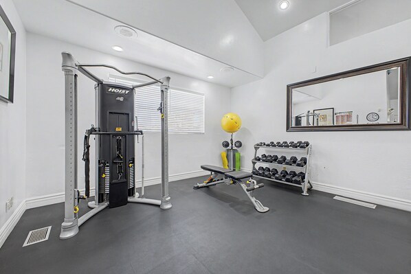A gym with exercise equipment, a bench, dumbbells, and a mirror.
