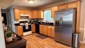 A kitchen with wooden cabinets, a stainless steel refrigerator, a stove, and a microwave. - Spacious double units dublex in Lawrenceville (Lawrenceville)