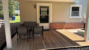 A covered patio with a wooden deck, a white door, and a brick wall. - Spacious double units dublex in Lawrenceville (Lawrenceville)