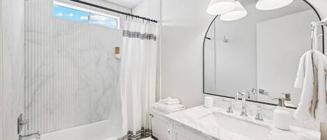 A modern bathroom with a bathtub, toilet, and vanity with a large mirror.
