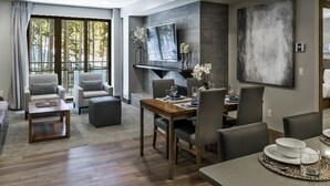 Un salon moderne comprenant un coin repas, une grande fenêtre et un téléviseur à écran plat fixé au mur.