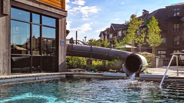 Une piscine dotée d’une grande structure tubulaire, entourée de bâtiments et d’arbres.