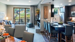 Une chambre d’hôtel moderne dotée d’un coin repas, d’une cuisine et d’un balcon offrant une vue sur l’extérieur.