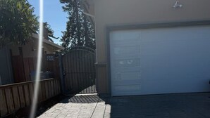 A paved driveway leading to a garage with a wooden fence and a warning sign.
