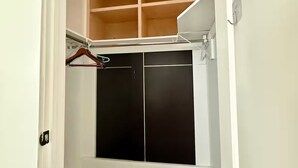A walk-in closet with open shelving, a hanging rod, and a mirrored closet door.