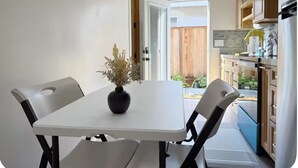 A compact kitchen with a dining table, chairs, and a small potted plant.