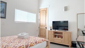 A bedroom with a bed, a TV, a wardrobe, and a door.