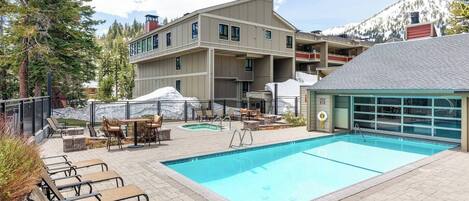 A pool area with lounge chairs and a building with multiple balconies.
