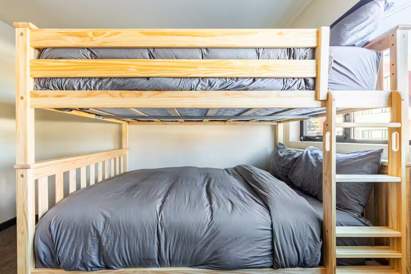 Un lit superposé avec une structure en bois et une literie grise.