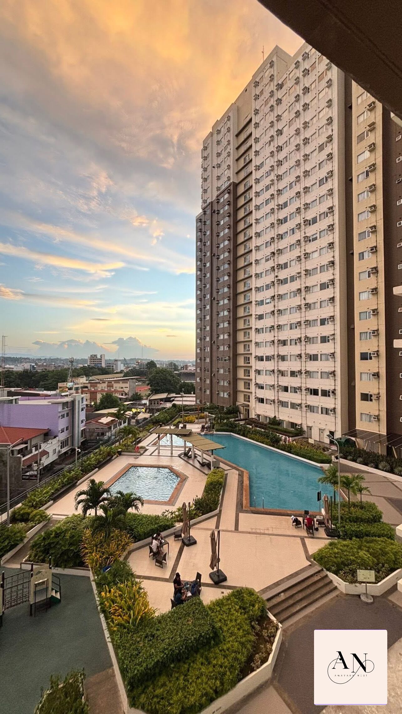 A high-rise building with a swimming pool and landscaped areas.