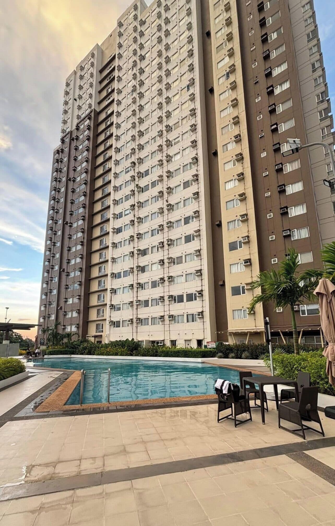 A high-rise residential building with a swimming pool and outdoor seating area.