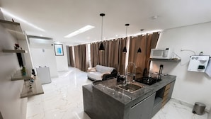 A modern kitchen with a marble countertop, a built-in stove, and a coffee machine. - Aconchego de Lugar - Eri & Douglas  - 4 (Belo Horizonte)