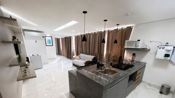 A modern kitchen with a marble countertop, a built-in stove, and a coffee machine. - Aconchego de Lugar - Eri & Douglas  - 4 (Belo Horizonte)