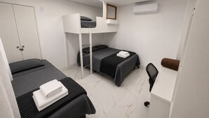 A modern, compact hotel room with a bunk bed, a desk, a chair, and a small seating area. - Aconchego de Lugar - Eri & Douglas  - 4 (Belo Horizonte)