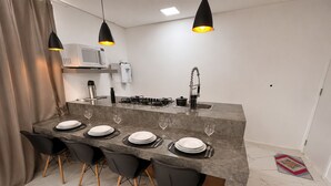 A modern kitchen with a marble countertop, black chairs, and pendant lighting. - Aconchego de Lugar - Eri & Douglas  - 4 (Belo Horizonte)