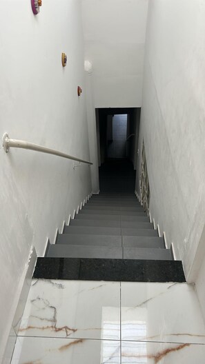 Un escalier avec une rampe, des murs blancs et un sol carrelé.