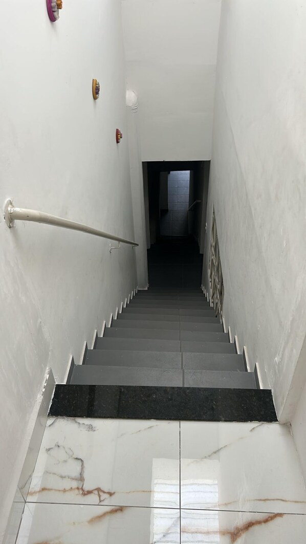 A staircase with a handrail, white walls, and a tiled floor. - Aconchego de Lugar - Eri&Douglas (Belo Horizonte)
