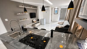 A modern kitchen with a gas stove, a sink, and pendant lighting. - Aconchego de Lugar - Eri & Douglas  - 4 (Belo Horizonte)