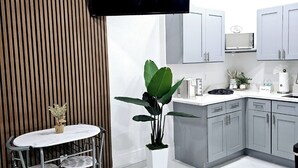 A modern kitchen with a flat-screen TV, a dining area with a white table and chairs, and a large potted plant. - ROMANTIC SUITE MAYDUNY (Tampa)