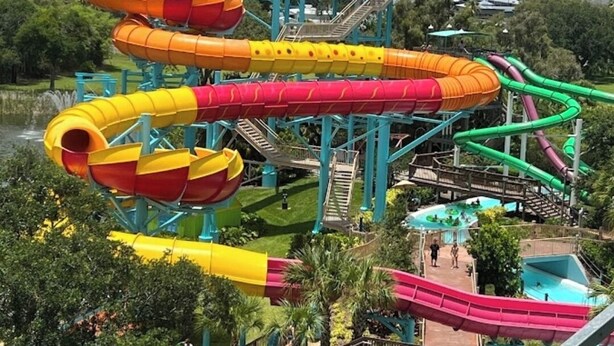 A water park with multiple water slides in various colors, a pool area, and a bridge structure. - ROMANTIC SUITE MAYDUNY (Tampa)
