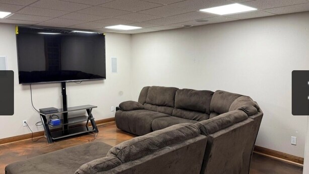 A room with a sectional sofa, a flat-screen TV, and a small table. - Bedrooms for rent in a very nice space (Joplin)