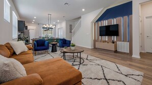 A spacious living area with a sofa, chairs, a coffee table, and a TV. - WI3277 - 5BR house near Disney with private pool (Davenport)