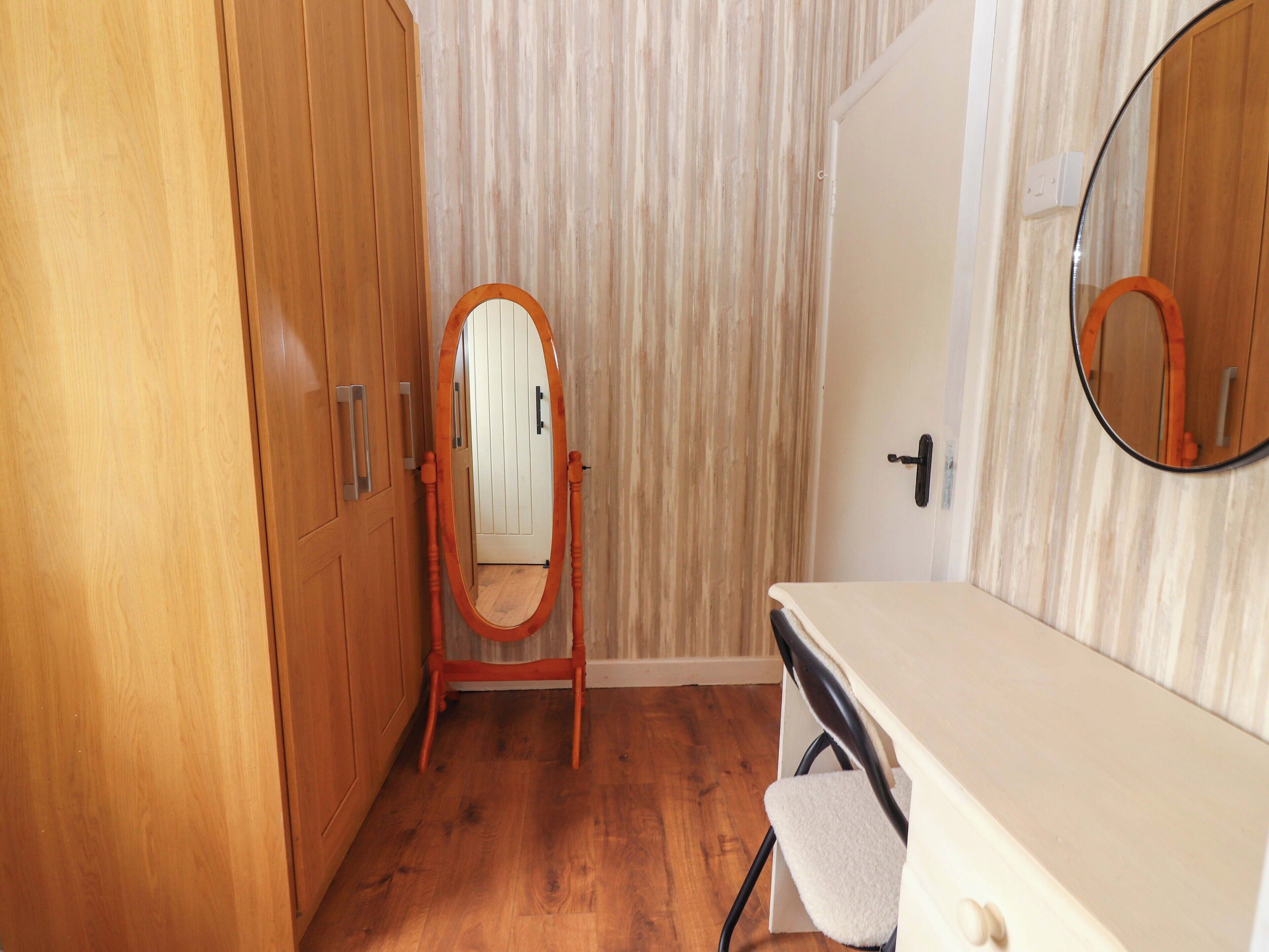 A bathroom with wooden cabinets, a vanity with a mirror, and a wooden floor.