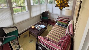 A sunroom with a ceiling fan, a star-shaped hanging light, a striped sofa, and a wicker chair. - 328 Cherry Close Walk to Downtown and Pool (Lakeside)