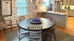 A dining area with a round table, wicker chairs, and a chandelier. - 328 Cherry Close Walk to Downtown and Pool (Lakeside)