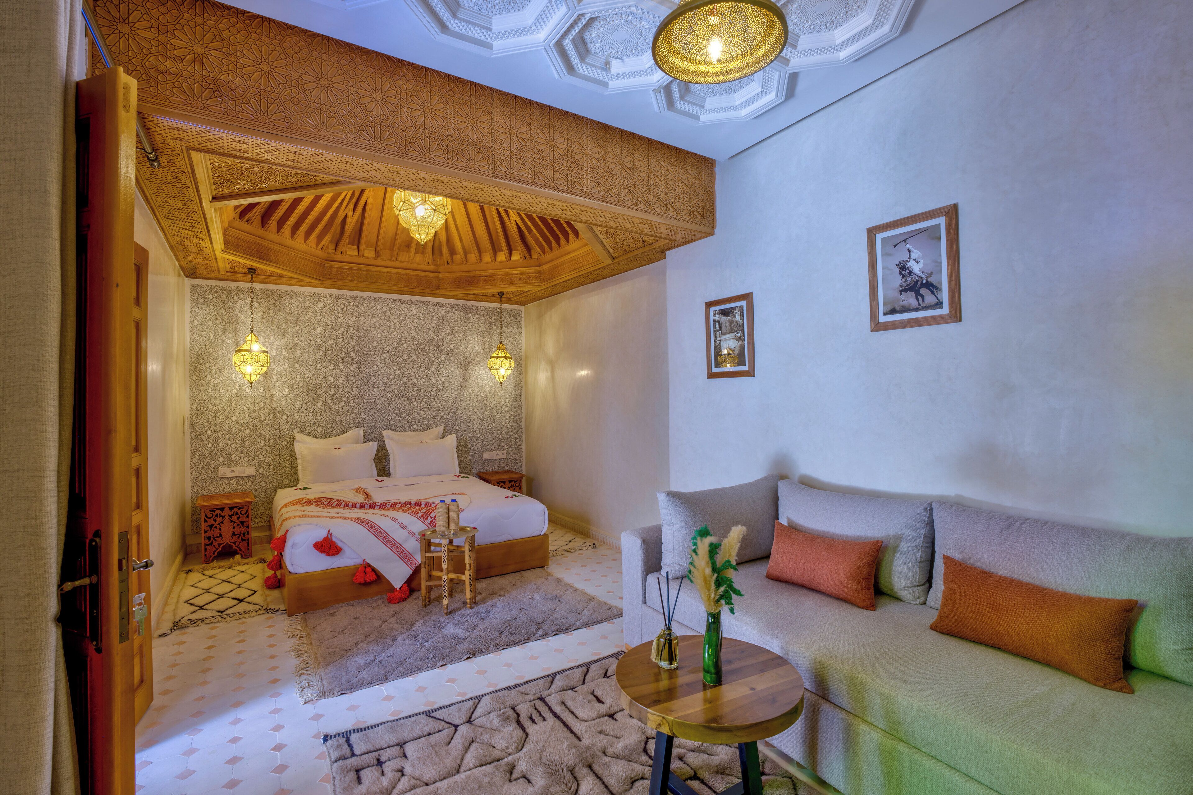 Une chambre à coucher comprenant un lit, un canapé, une petite table et un plafond décoratif.