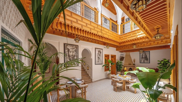 A spacious interior with a high ceiling, wooden beams, and a patterned floor. There are multiple seating areas and potted plants. - Riad Al Ghazlan  (Marrakech)