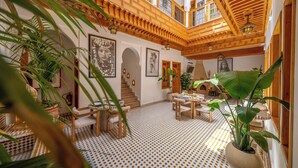 A spacious interior with a high ceiling, wooden beams, patterned flooring, and multiple seating areas. - Riad Al Ghazlan  (Marrakech)