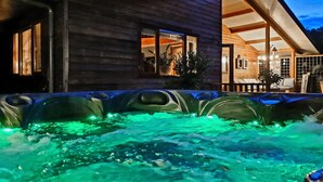 A wooden cabin with a hot tub illuminated by green lights. - Gorgeous home in Erm with WiFi (Erm)