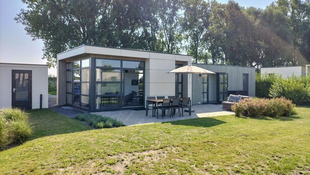 Una casa moderna amb una zona de pati, una taula de dinar i seients exteriors.