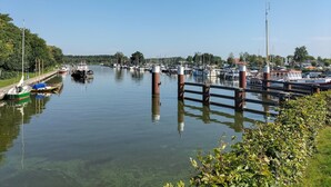 Un port esportiu amb vaixells amarrats al llarg de l'aigua, un pont i un cel serè.