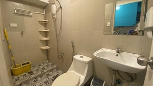Un baño con inodoro, lavamanos, ducha y un trapeador.