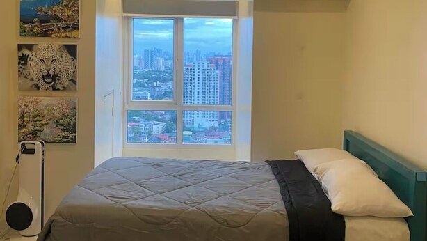 Un dormitorio con cama, ventana con vistas a la ciudad, aire acondicionado e iluminación en el techo.