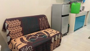 Una kitchenette pequeña con un refrigerador, un microondas y un dispensador de agua verde.