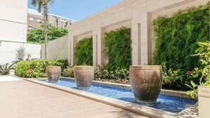 Un área de piscina con macetas grandes y una pared cubierta de vegetación.