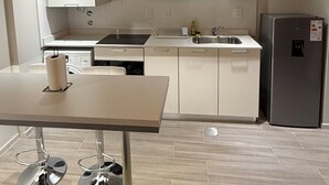 Une cuisine moderne avec des armoires blanches, un réfrigérateur en acier inoxydable, un four à micro-ondes et un évier.