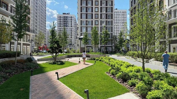 A residential area with modern apartment buildings, a well-maintained lawn, and a paved walkway. - New England Ecoloft Studios (Kyiv)