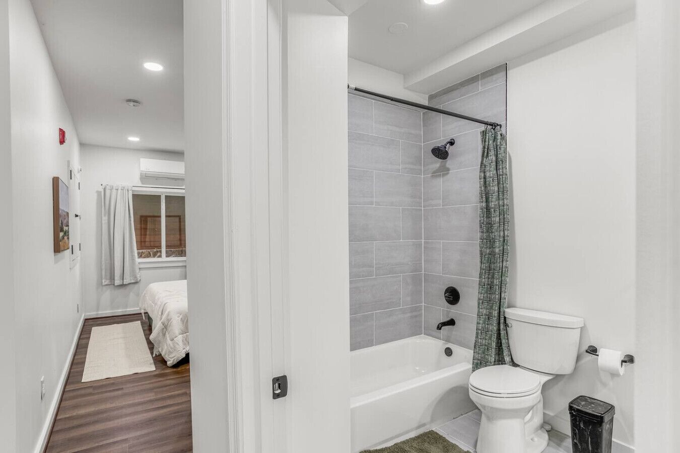 A modern bathroom with a bathtub, toilet, and shower area.