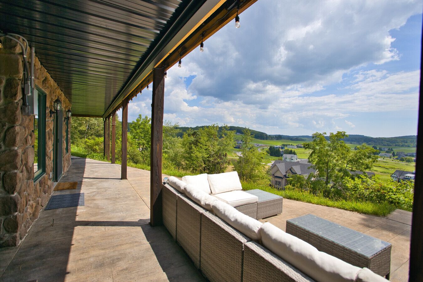 A covered outdoor seating area with stone walls and a view of a rural landscape.