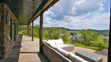 A covered outdoor seating area with stone walls and a view of a rural landscape.